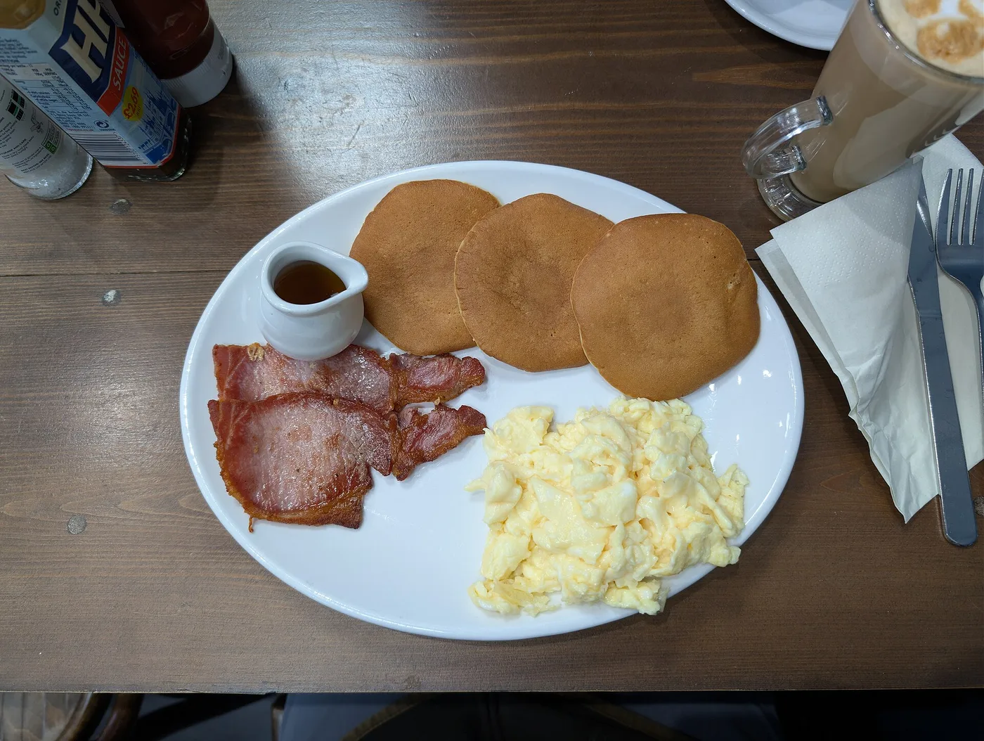 A breakfast plate of pancakes, bacon and scrambled eggs with a latte. The photo was not taken in Jacksonville.