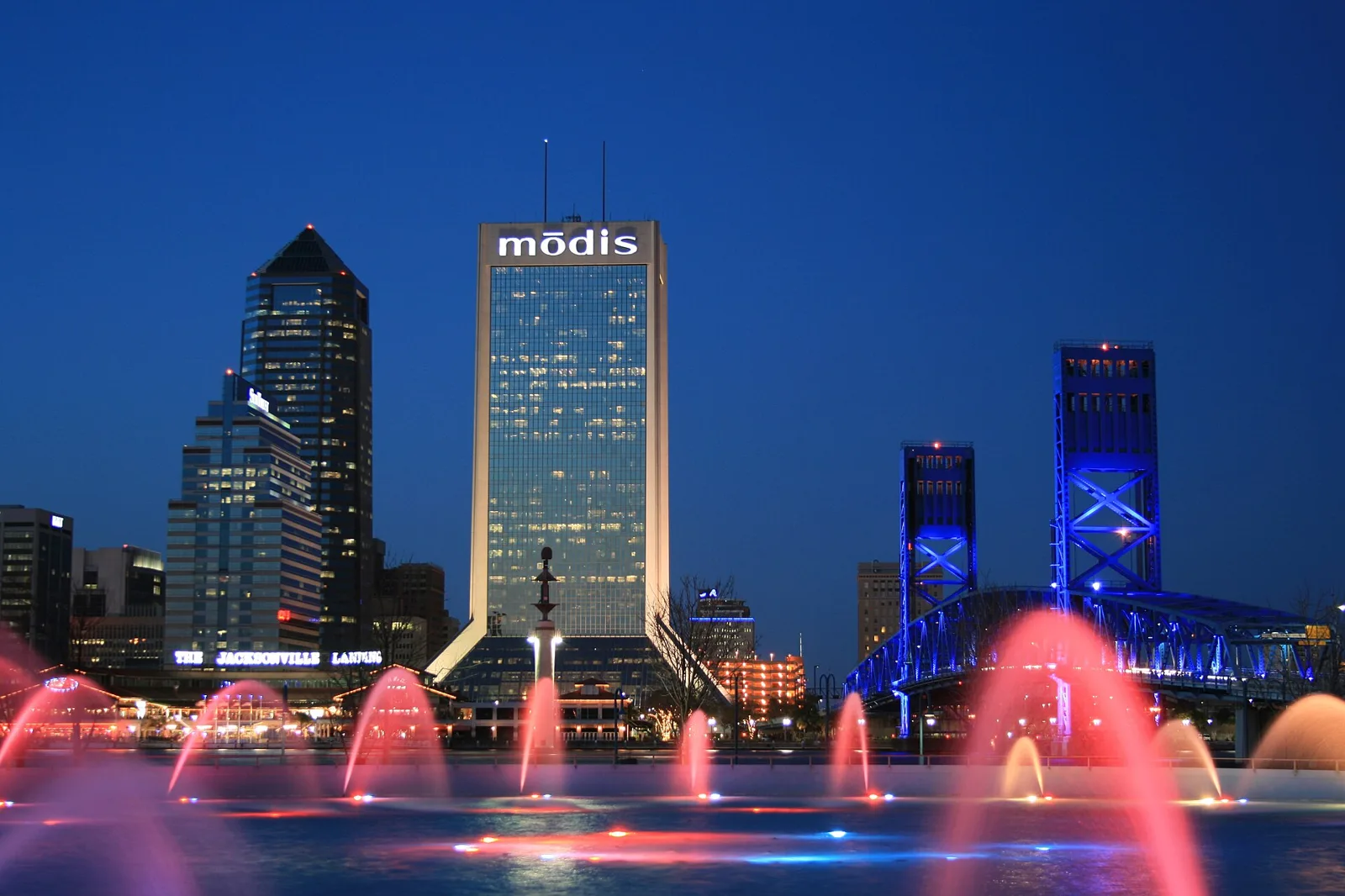 Friendship Fountain lit up at night on the Southbank, with the Main Street Bridge and the downtown skyline behind it.