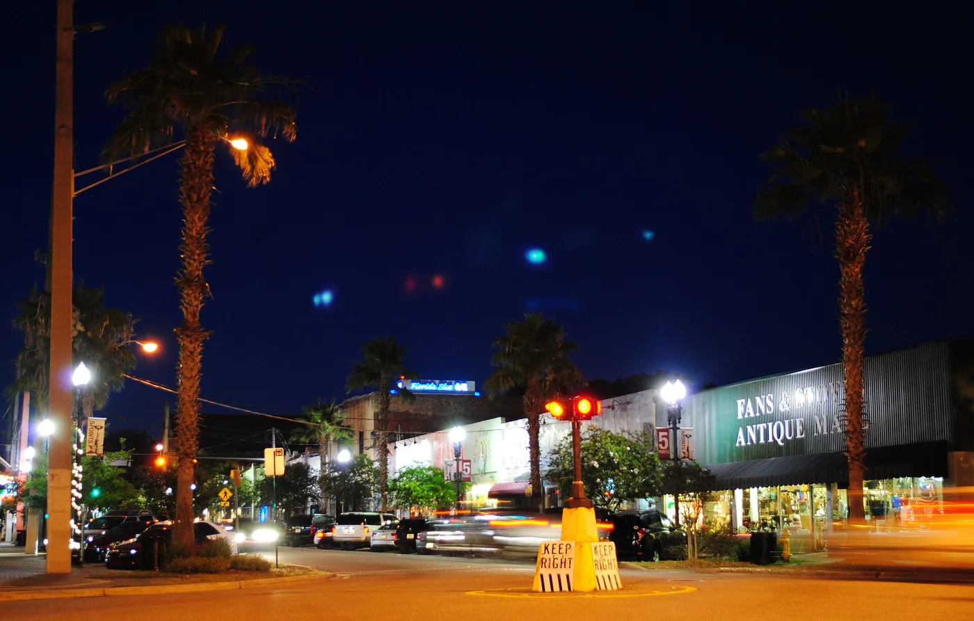 Five Points in Riverside at night, with palm trees, shops and the Keep Right sign in the middle of the intersection, in Jacksonville.